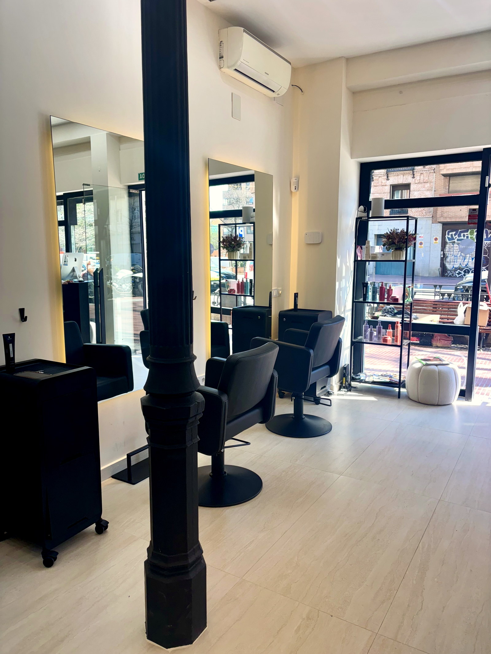 Vista amplia del salón Belyra con sillas de barbero, espejos y ventanal